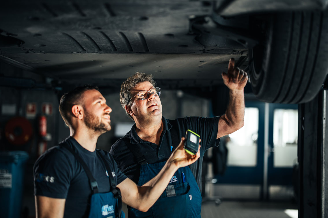 twee Ames Volkswagen monteurs onder een auto met een zaklamp