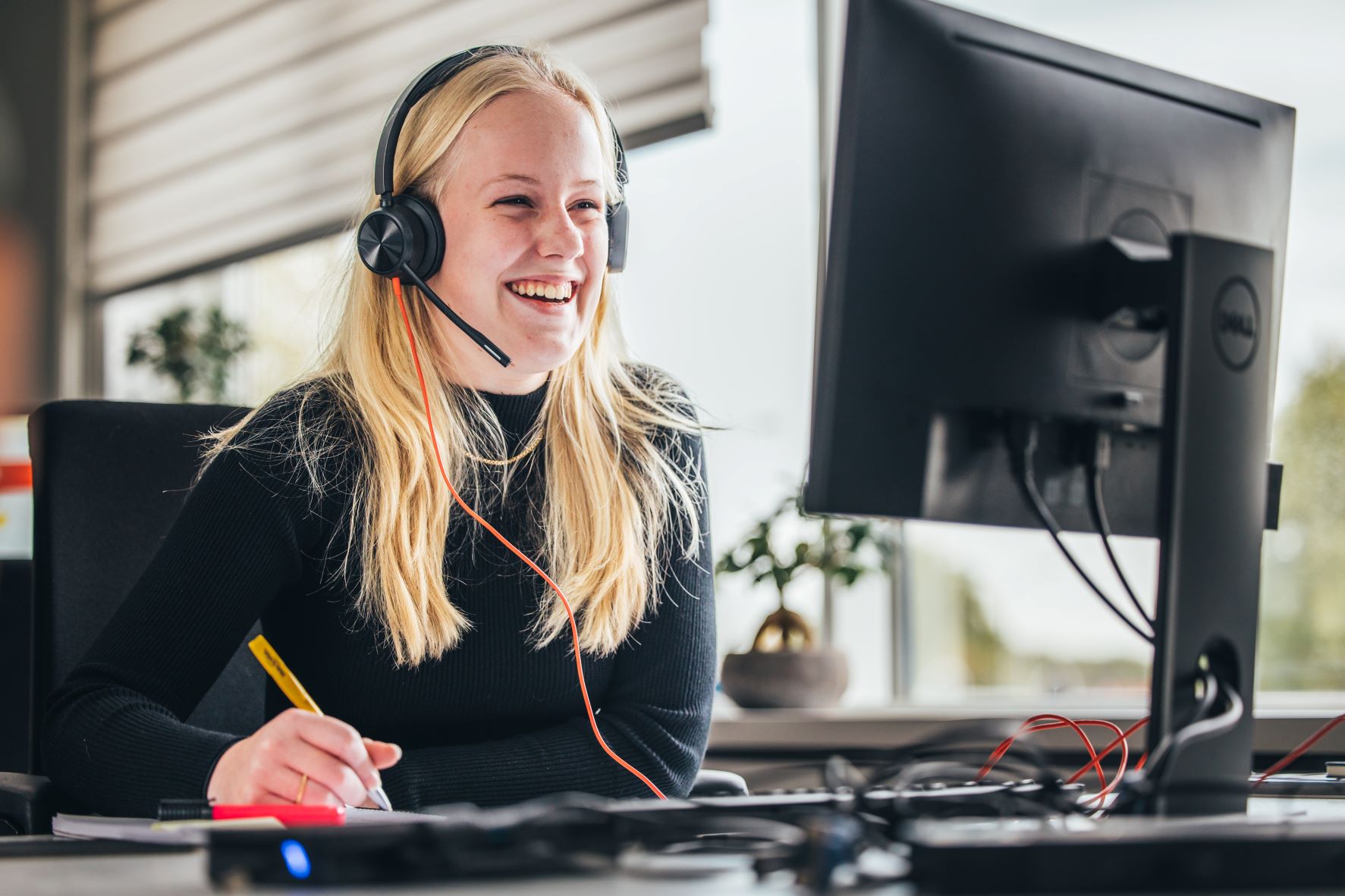 Telefoniste vrouw achter computer lachend met headset