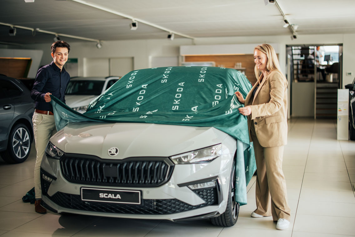 Man en vrouw halen een doek van een auto af