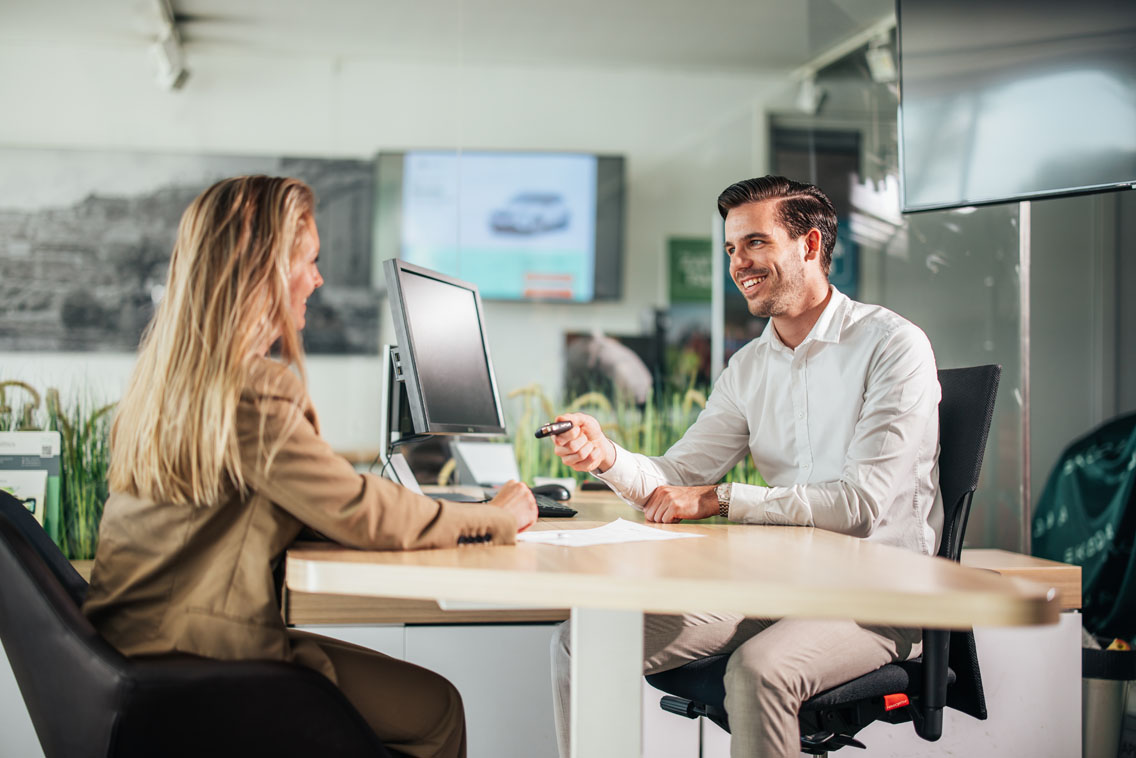 Man en vrouw in overleg bij een tafel in Ames Skoda showroom