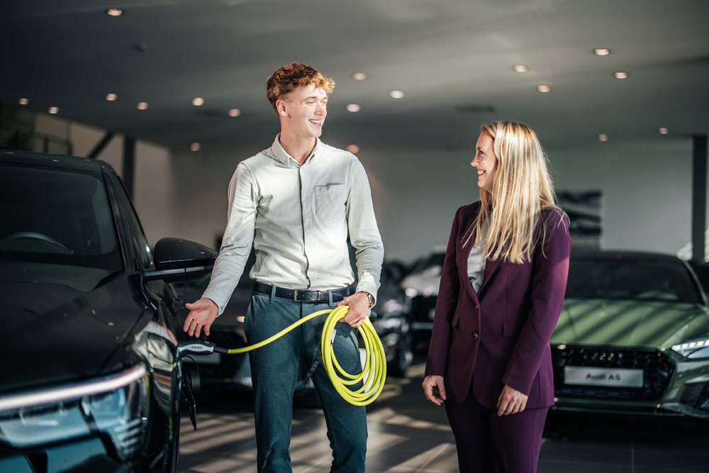 Service adviseur doet oplaadkabel in een auto