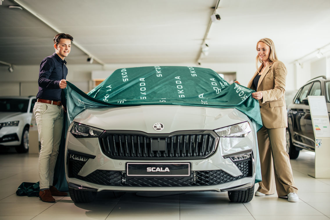 Man en vrouw halen een doek van een auto af