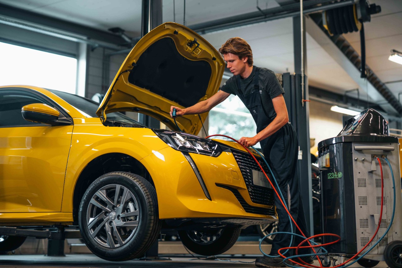 Technisch specialist Peugeot bij motorkap van gele auto